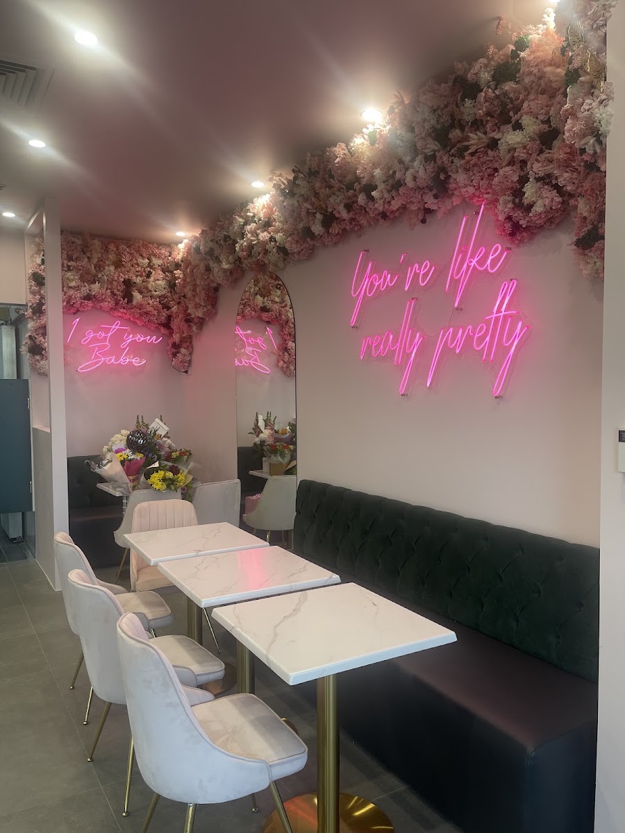 Inside The Sweetest Spot: a pink flower wall, pink neon signs, marble tables and velvet chairs